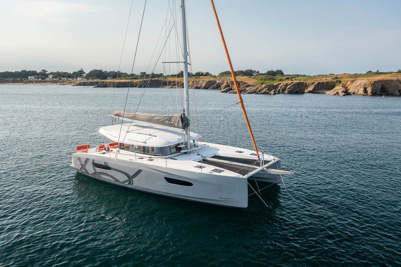 Le catamaran Excess 14 AGAPE au mouillage le long d'une côte rocheuse